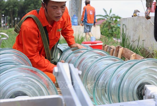 Công nhân Công ty Cổ phần Tập đoàn Đầu tư thương mại công nghiệp Việt Á kiểm tra thiết bị trụ sứ cách điện trước khi được treo lên cột số 352, thuộc địa bàn xã Vũ Ninh, tỉnh Phú Thọ. Ảnh: Vũ Sinh - TTXVN