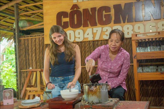 Chị Lisa Pfabigan (du khách Áo) trải nghiệm làm bánh dân gian ở Cồn Sơn. Ảnh: Thanh Liêm - TTXVN