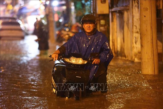 Người dân phải dắt bộ xe qua “biển nước” trên đường Dường Văn Cam (TP. Hồ Chí Minh) sau cơn mưa lớn chiều tối 5/8/2025. Ảnh: TTXVN phát