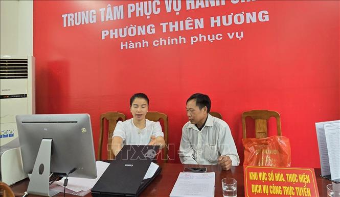 Chuyên viên phường Thiên Hương hỗ trợ người dân nộp thủ tục hành chính trên cổng dịch vụ công quốc gia. Ảnh: Minh Thu-TTXVN