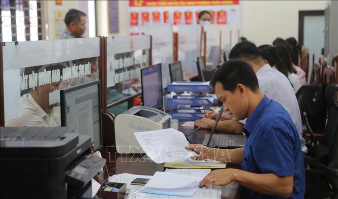 Chuyên viên lĩnh vực xây dựng, giao thông, công thương phường Thiên Hương kiểm tra thông tin hồ sơ công dân nộp. Ảnh: Minh Thu-TTXVN