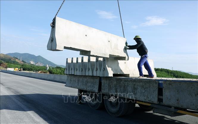 Công nhân nhà thầu triển khai lắp đặt dải phân cách cứng trên tuyến. Ảnh: Quốc Khánh - TTXVN