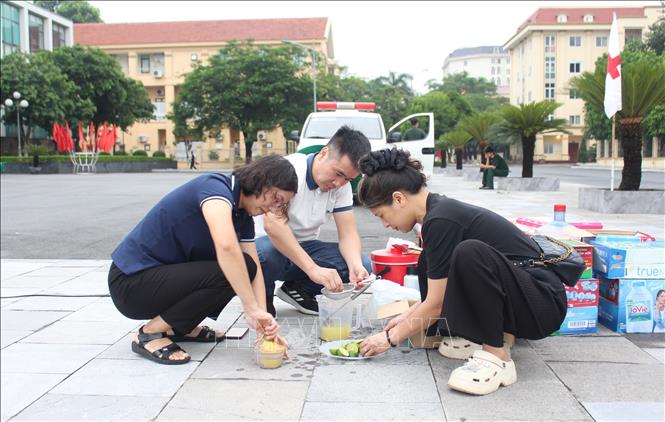 Các cán bộ, giáo viên, phụ huynh trường THPT Phan Đình Phùng (Hà Nội) chuẩn bị nước uống cho học sinh. Ảnh: Nguyễn Cúc - TTXVN