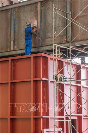 Công nhân đang tập trung lắp đặt hệ thống lò đốt tại khu nhà xưởng xử lý chất thải công nghiệp. Ảnh: Hoàng Hiếu - TTXVN