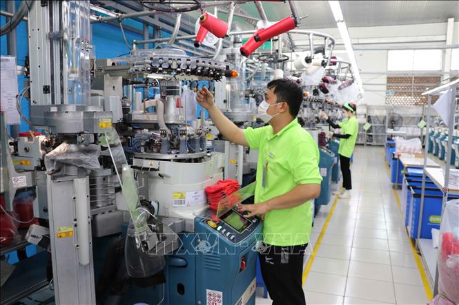 Công nhân nhà máy Sung Hwa Vina (vốn Hàn Quốc) tại KCN Hòa Bình (Tây Ninh) kiểm tra sợi trên máy dệt tất. Ảnh: Minh Hưng – TTXVN