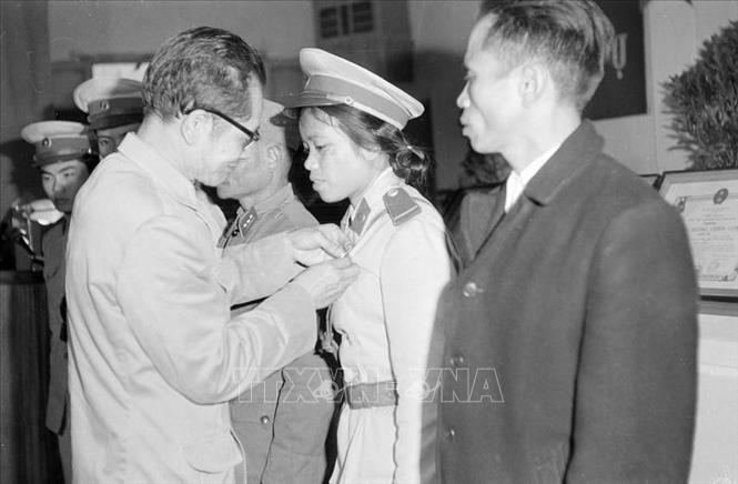 Chủ tịch Ủy ban hành chính Hà Nội Trần Duy Hưng gắn Huy hiệu Hồ Chủ tịch cho Hạ sĩ Nguyễn Thị Khuyến, công an Đồn 44 có thành tích phục vụ chiến thắng đợt tập kích không quân chiến lược của Mỹ vào Hà Nội (12/1972). Ảnh: TTXVN