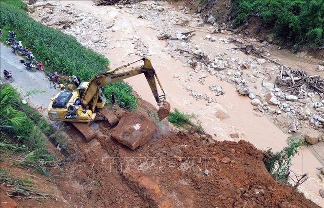 Máy xúc được huy động đến các điểm sạt lở, nhanh chóng san ủi để các phương tiện sớm được lưu thông. Ảnh: Quang Quyết - TTXVN