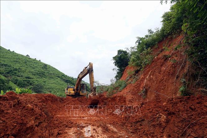 Máy xúc được huy động đến các điểm sạt lở, nhanh chóng san ủi để các phương tiện sớm lưu thông. Ảnh: Quang Quyết - TTXVN