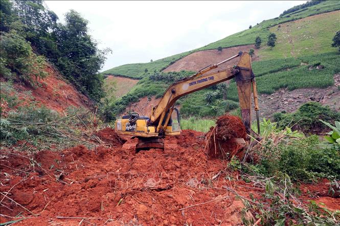 Máy xúc được huy động đến các điểm sạt lở, nhanh chóng san ủi để các phương tiện sớm lưu thông. Ảnh: Quang Quyết - TTXVN