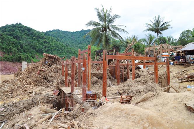 Ngôi nhà sàn bị lũ phá hủy gây thiệt hại nặng nề, chỉ còn trơ khung gỗ. Phần tầng 1 của căn nhà đã bị vùi lấp chìm trong lớp bùn cát sâu hơn 3m. Ảnh: Xuân Tiến - TTXVN 