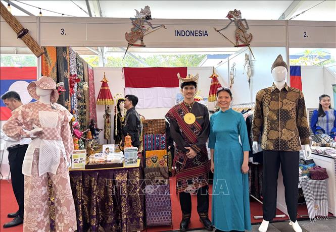 Phóng viên (áo dài) “check-in” không gian trưng bày của Indonesia tại Lễ kỷ niệm 58 năm Ngày thành lập ASEAN. Ảnh: Viên Luyến – Phóng viên TTXVN tại Malaysia.
