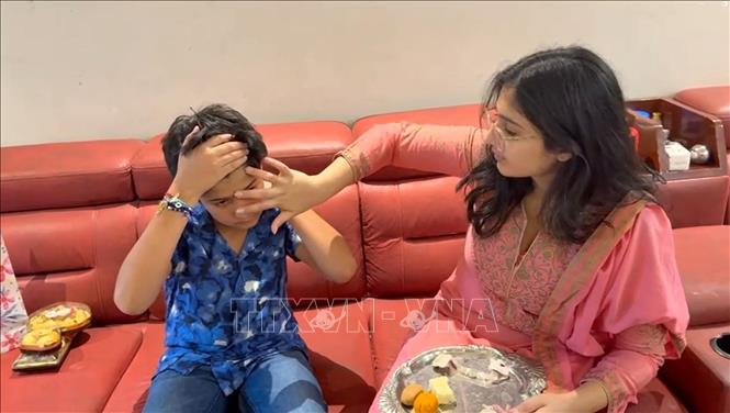 Chị gái chấm “tilak” (dấu đỏ) lên trán và cầu nguyện cho anh em trai được bình an, hạnh phúc. Ảnh: Ngọc Thúy - PV TTXVN tại Ấn Độ