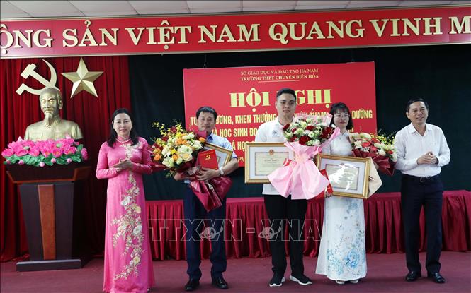 Phó Bí thư Thường trực Tỉnh ủy Ninh Bình Đinh Thị Lụa tặng hoa, khen thưởng cho em Đỗ Trung Kiên và giáo viên bồi dưỡng đội tuyển Hóa học Trường THPT chuyên Biên Hòa. Ảnh: Đại Nghĩa -TTXVN