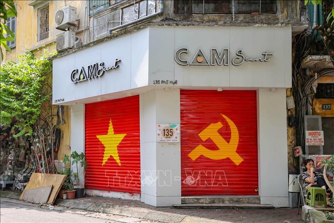 Biểu tượng cờ búa liềm và cờ đỏ sao vàng được trang trí trên một cửa hàng ở Phố Huế thể hiện niềm tự hào và tình yêu đối với Tổ quốc. Ảnh: Vũ Quang - TTXVN