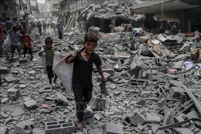 Trẻ em Palestine nhặt nhạnh đồ dùng còn lại sau vụ không kích của Israel xuống khu vực Al-Rimal, phía Tây thành phố Gaza, ngày 8/8/2025. Ảnh: THX/TTXVN 
