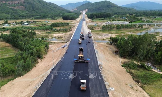 Nhà thầu thi công thảm nhựa những đoạn cuối cùng trên tuyến. Ảnh: Quốc Khánh - TTXVN