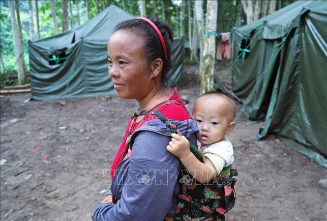 Mẹ địu con đi dạo chơi trong khu nhà bạt vào buổi sáng sớm. Ảnh: Xuân Tiến  - TTXVN 
