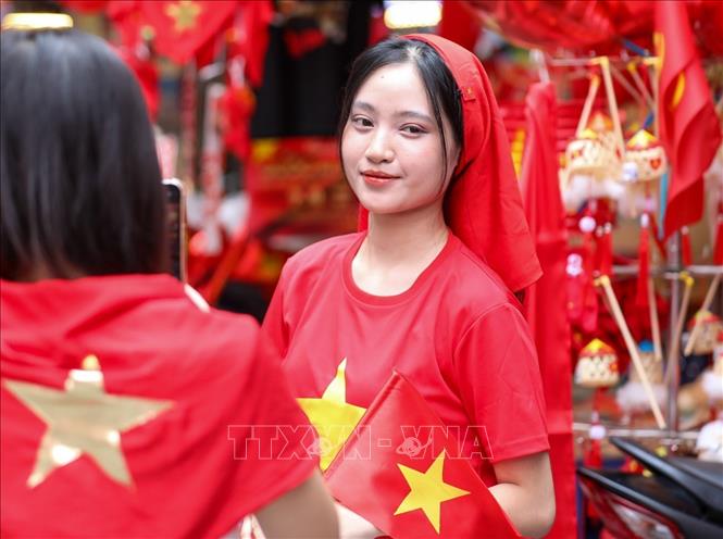 Các bạn trẻ lưu lại khoảnh khắc với hình ảnh cờ Tổ quốc tại phố Hàng Mã, phường Hoàn Kiếm. Ảnh: Khánh Hoà - TTXVN