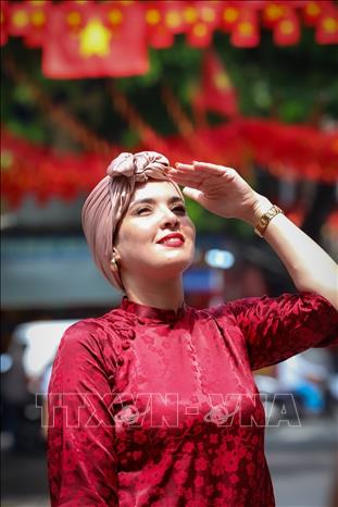 Du khách nước ngoài thích thú lưu lại khoảnh khắc với những con phố ngập tràn sắc đỏ của Thủ đô. Ảnh: Khánh Hoà - TTXVN