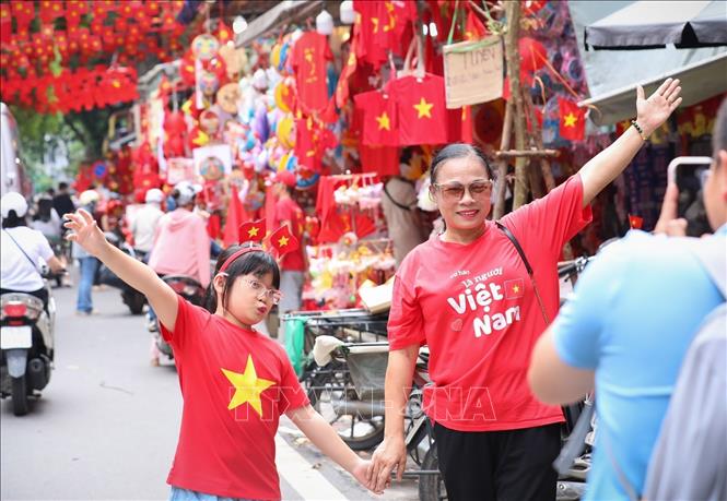 Nhiều người dân lưu lại khoảnh khắc với hình ảnh cờ Tổ quốc tại phố Hàng Mã, phường Hoàn Kiếm. Ảnh: Khánh Hoà - TTXVN