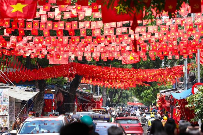 Các bạn trẻ lưu lại khoảnh khắc với hình ảnh cờ Tổ quốc tại phố Hàng Mã, phường Hoàn Kiếm. Ảnh: Khánh Hoà - TTXVN