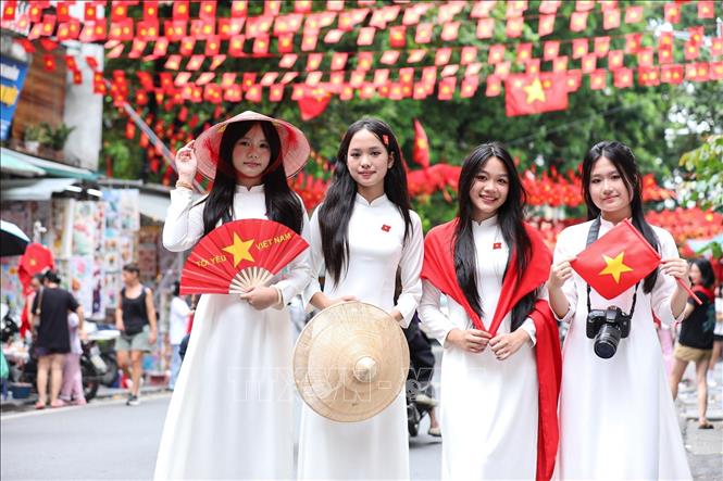 Các bạn trẻ lưu lại khoảnh khắc với hình ảnh cờ Tổ quốc tại phố Hàng Mã, phường Hoàn Kiếm. Ảnh: Khánh Hoà - TTXVN