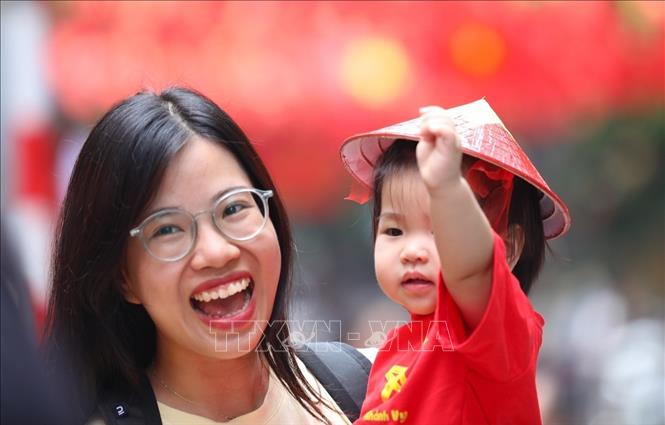 Nhiều người dân lưu lại khoảnh khắc với hình ảnh cờ Tổ quốc tại phố Hàng Mã, phường Hoàn Kiếm. Ảnh: Khánh Hoà - TTXVN