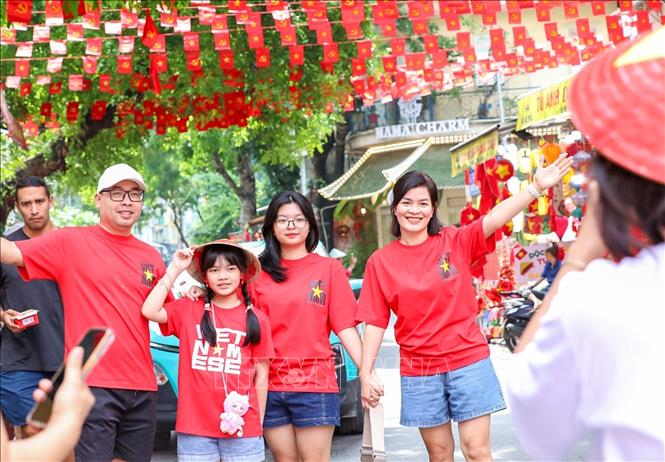Nhiều người dân lưu lại khoảnh khắc với hình ảnh cờ Tổ quốc tại phố Hàng Mã, phường Hoàn Kiếm. Ảnh: Khánh Hoà - TTXCN