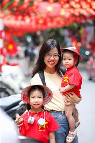 People pose for a photo with national flags on Hang Ma street, Hoan Kiem ward. VNA Photo: Khánh Hòa 