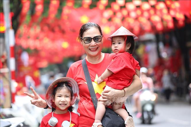 People pose for a photo with national flags on Hang Ma street, Hoan Kiem ward. VNA Photo: Khánh Hòa 