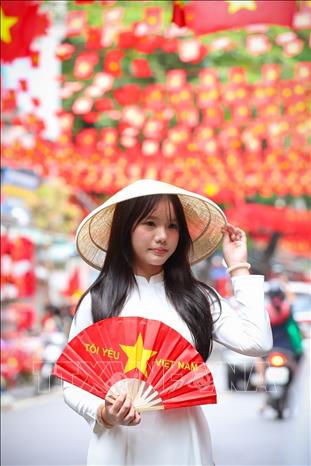 People pose for a photo with national flags on Hang Ma street, Hoan Kiem ward. VNA Photo: Khánh Hòa 