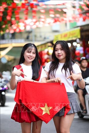 People pose for a photo with national flags on Hang Ma street, Hoan Kiem ward. VNA Photo: Khánh Hòa 