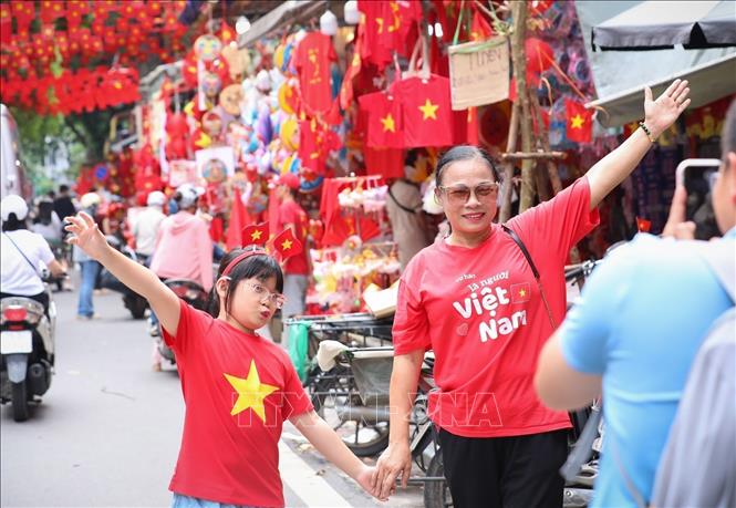 People pose for a photo with national flags on Hang Ma street, Hoan Kiem ward. VNA Photo: Khánh Hòa 