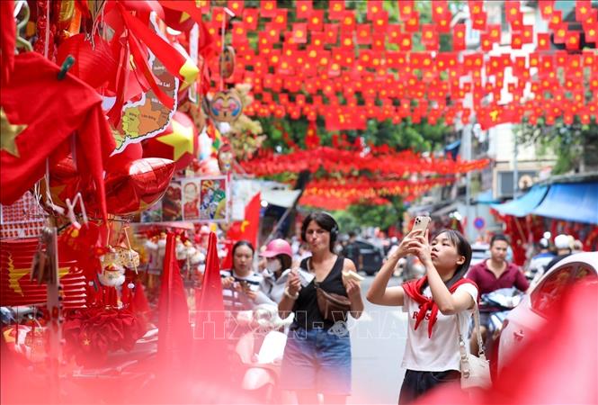 People capture moments with national flags on Hang Ma street, Hoan Kiem ward. VNA Photo: Khánh Hòa 