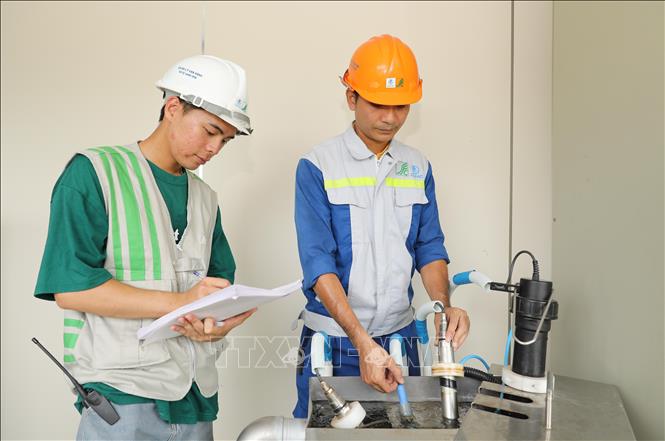 Các kỹ sư đang giám sát quá trình bơm chất javen để khử trùng nước thải sau khi qua các công đoạn lắng, lọc. Ảnh: Thành Phương – TTXVN