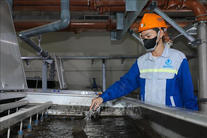 Các kỹ sư đang vận hành hệ thống xử lý bùn trọng lực kiểu băng tải để tách lọc bùn từ các sông đổ về. Ảnh: Thành Phương – TTXVN