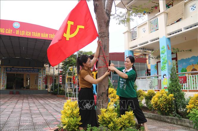 Giáo viên trường Mầm non Bùi Hữu Diên (xã Hồng Minh) treo cờ chuẩn bị cho năm học mới. Ảnh: Thu Hoài - TTXVN