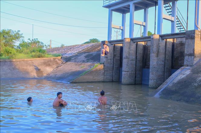 Một thiếu niên nhảy từ trên cống xả tiêu Trạm bơm Hữu Bị xuống sông dưới sự cổ vũ của các bạn. Ảnh: Công Luật - TTXVN