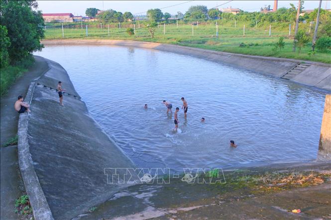 Tầm chiều tối, tại khu vực cống xả tiêu Trạm bơm Hữu Bị, địa phận giáp ranh giữa phường Nam Định và phường Thiên Trường, tỉnh Ninh Bình có rất đông thanh thiếu niên xuống tắm bất chấp nguy hiểm. Ảnh: Công Luật - TTXVN