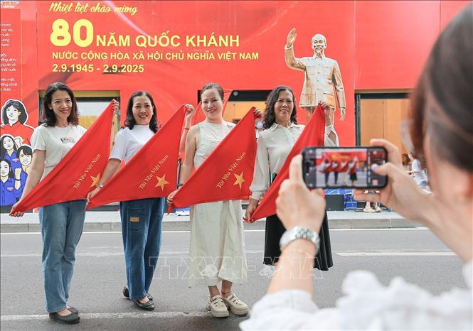 Check-in trong sắc cờ đỏ sao vàng, người dân lưu lại khoảnh khắc ý nghĩa tại vườn hoa Lý Thái Tổ. Ảnh: Lê Đông - TTXVN