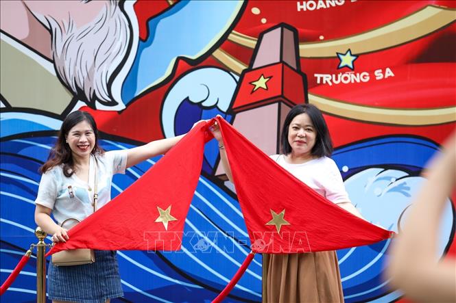 Trong những ngày gần đến Đại lễ, nhiều người dân xuống đường chụp ảnh với hình ảnh lá cờ Tổ quốc để thể hiện tình yêu nước và niềm tự hào dân tộc. Ảnh: Khánh Hoà - TTXVN