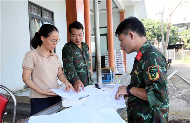 Lực lượng quân đội và lãnh đạo xã Huổi Một xem bản thiết kế nhà lắp ghép để xây dựng cho nhân dân bị ảnh hưởng, thiệt hại do lũ quét, sạt lở đất. Ảnh: Quang Quyết - TTXVN