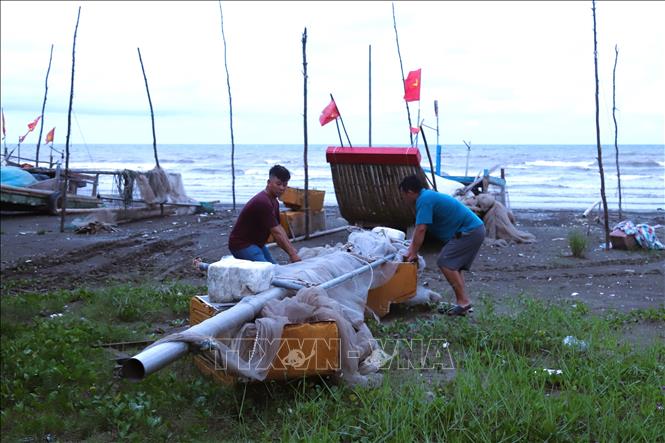 Ngư dân làng biển thu dọn ngư lưới cụ mang về nhà để tránh triều cường, sóng lớn xảy ra gây hư hại, mất mát. Ảnh: Xuân Tiến - TTXVN 