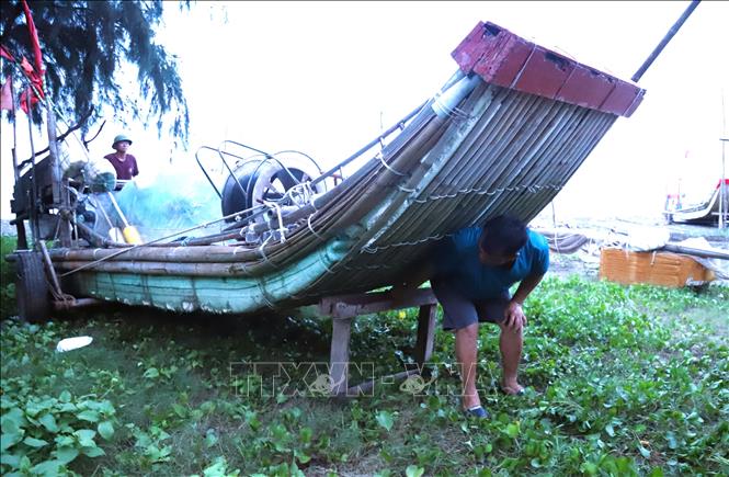 Ngư dân kiểm tra, kê mũi bè mảng chắc chắn tại khu vực tránh trú triều cường, sóng lớn. Ảnh: Xuân Tiến - TTXVN 
