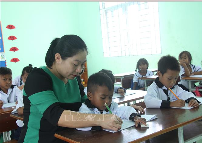 Cô Bùi Thị Hương, Trường Tiểu học Phước Thắng, xã Bác Ái, tỉnh Khánh Hòa cầm bút và tay của trẻ để hướng dẫn trẻ cách tập viết chữ tiếng Việt. Ảnh: Phan Sáu - TTXVN