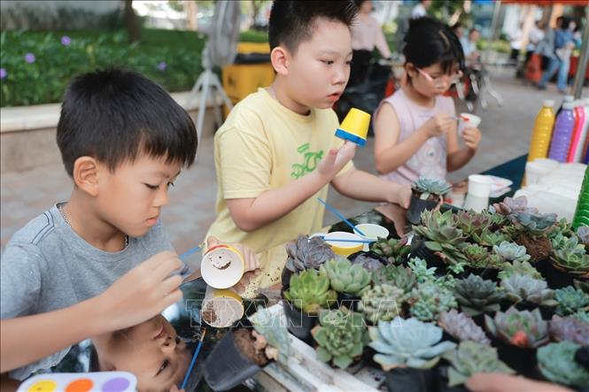 Các bạn nhỏ tự tay trang trí món quà là chậu cây mình vừa đổi được. Ảnh: Minh Quyết - TTXVN