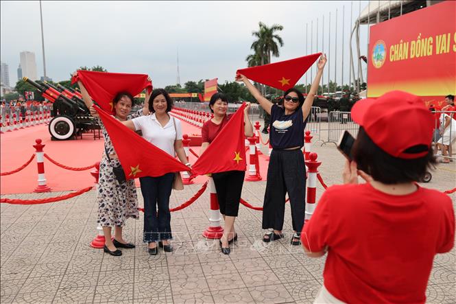 Một gia đình tạo dáng cùng cờ Tổ quốc để chụp ảnh lưu niệm cùng dàn pháo. Ảnh: Vũ Quang - TTXVN