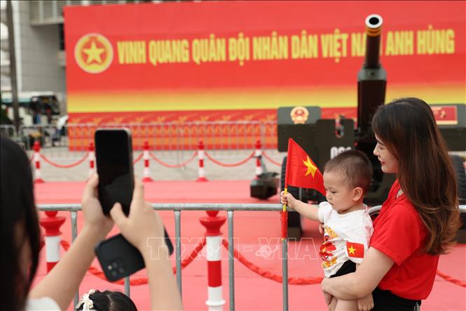 Các em nhỏ được bố mẹ cho mang cờ Tổ quốc để chụp ảnh cùng dàn pháo lễ. Ảnh: Vũ Quang - TTXVN