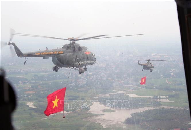 Biên đội máy bay trực thăng của Quân chủng Phòng không - Không quân treo cờ Đảng và cờ Tổ quốc bay vào khu vực trung tâm Thủ đô Hà Nội. Ảnh: Trọng Đức - TTXVN