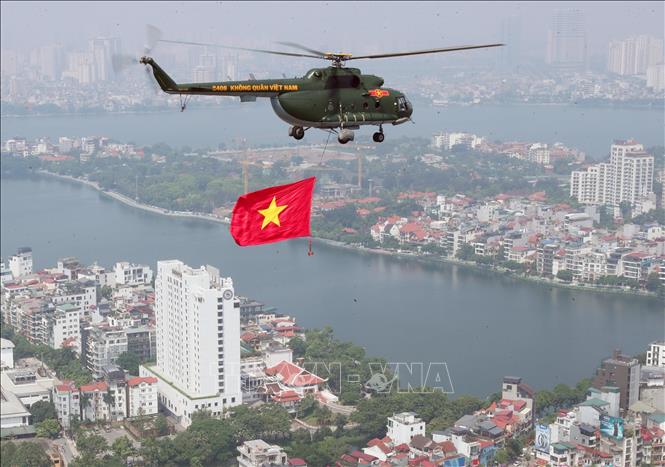 Biên đội máy bay trực thăng của Quân chủng Phòng không - Không quân treo cờ Đảng và cờ Tổ quốc bay vào khu vực trung tâm Thủ đô Hà Nội. Ảnh: Trọng Đức - TTXVN